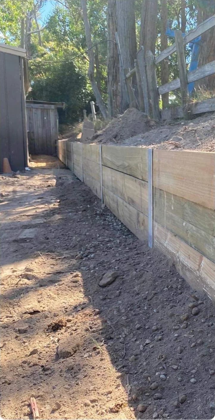 The same side yard cleared, with a new timber sleeper retaining wall along the slope